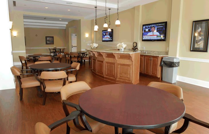 A cozy lounge area with wooden dining tables and chairs, featuring televisions on the walls.