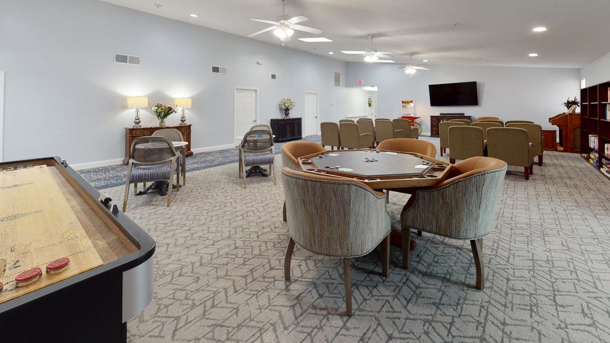 A spacious living and dining area with modern furnishings, including tables and chairs, a television, and a ceiling fan.