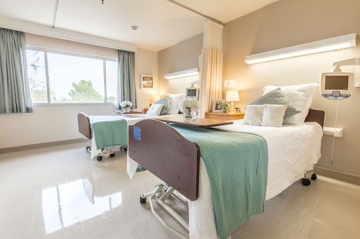 A well-lit, modern hospital room featuring two patient beds.