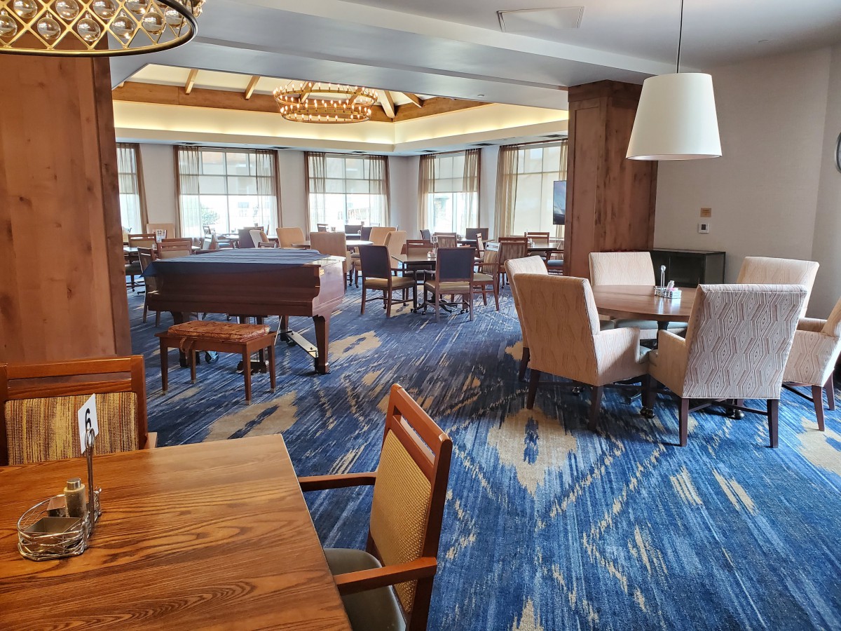 A modern dining area with tables and chairs arranged under ambient lighting.