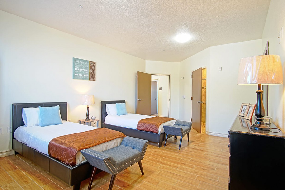 A spacious bedroom featuring twin beds, modern decor, and wooden flooring.