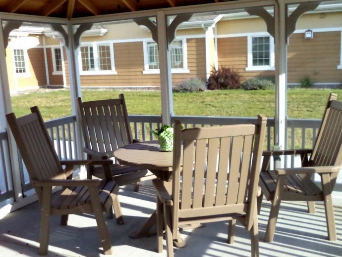A cozy gazebo featuring a wooden table and chairs on a sunny day.