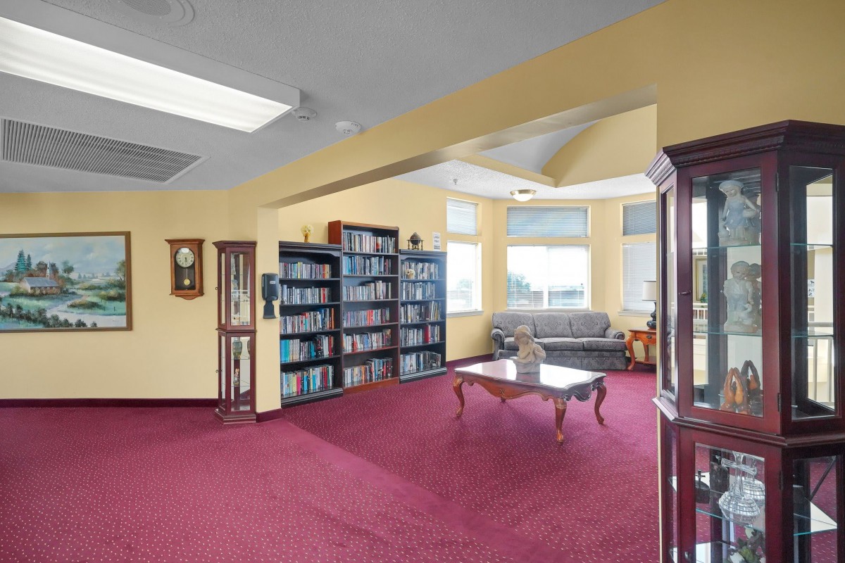 A cozy library corner with bookshelves, a sofa, and natural light.