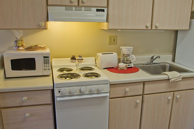 A small kitchen setup with essential appliances including a stove, microwave, toaster, and coffee maker.