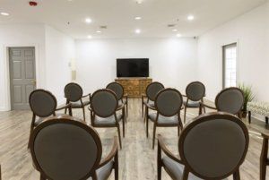 An empty conference room with arranged chairs facing a television.