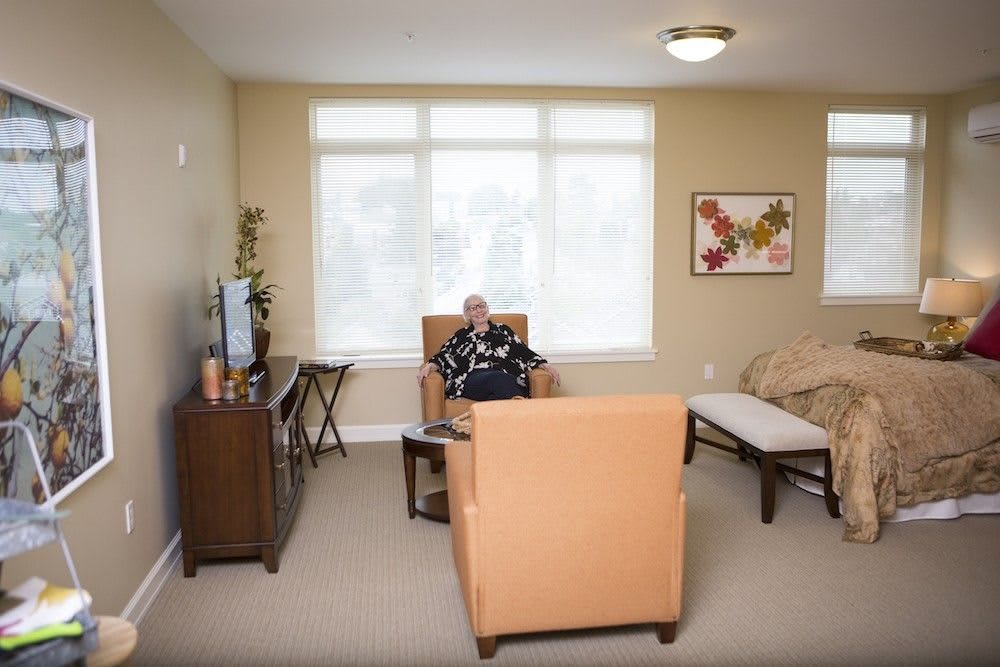 A cozy living room with a person sitting in an armchair, watching television.