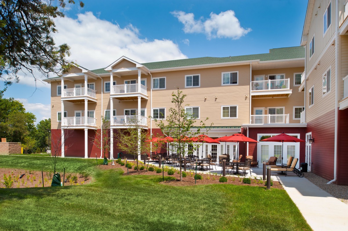 A modern hotel building with multiple balconies and a landscaped outdoor seating area.
