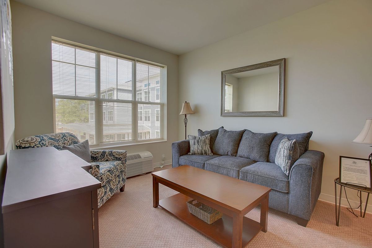 A cozy living room with a sofa, coffee table, and ample natural light coming through the window.