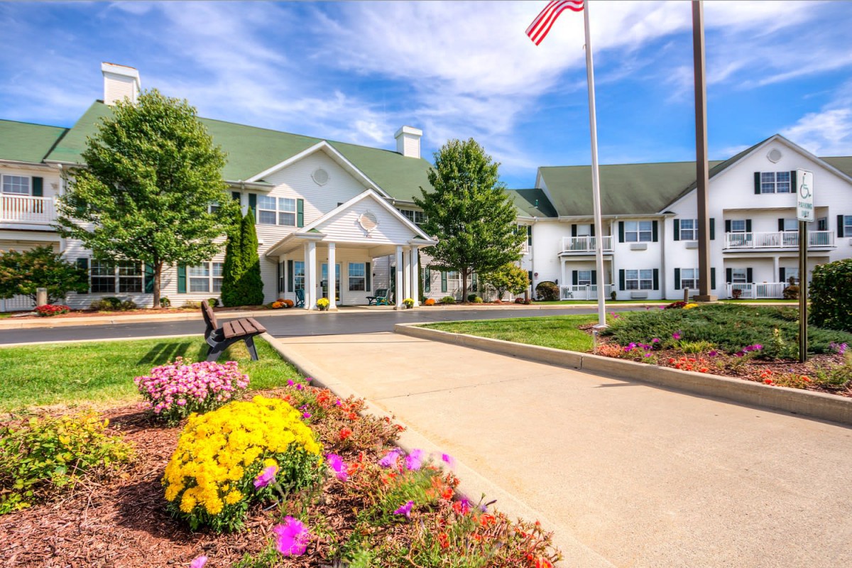 A scenic view of a well-maintained building with vibrant landscaping and an American flag waving in the front.