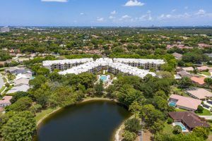 Aerial view of a residential complex surrounded by greenery and a small lake.
