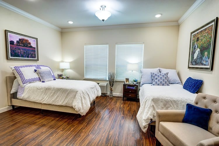 A cozy bedroom with twin beds, wooden flooring, and soft lighting.