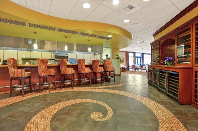 A modern restaurant interior featuring a stylish bar area with unique decorative flooring and ambient lighting.