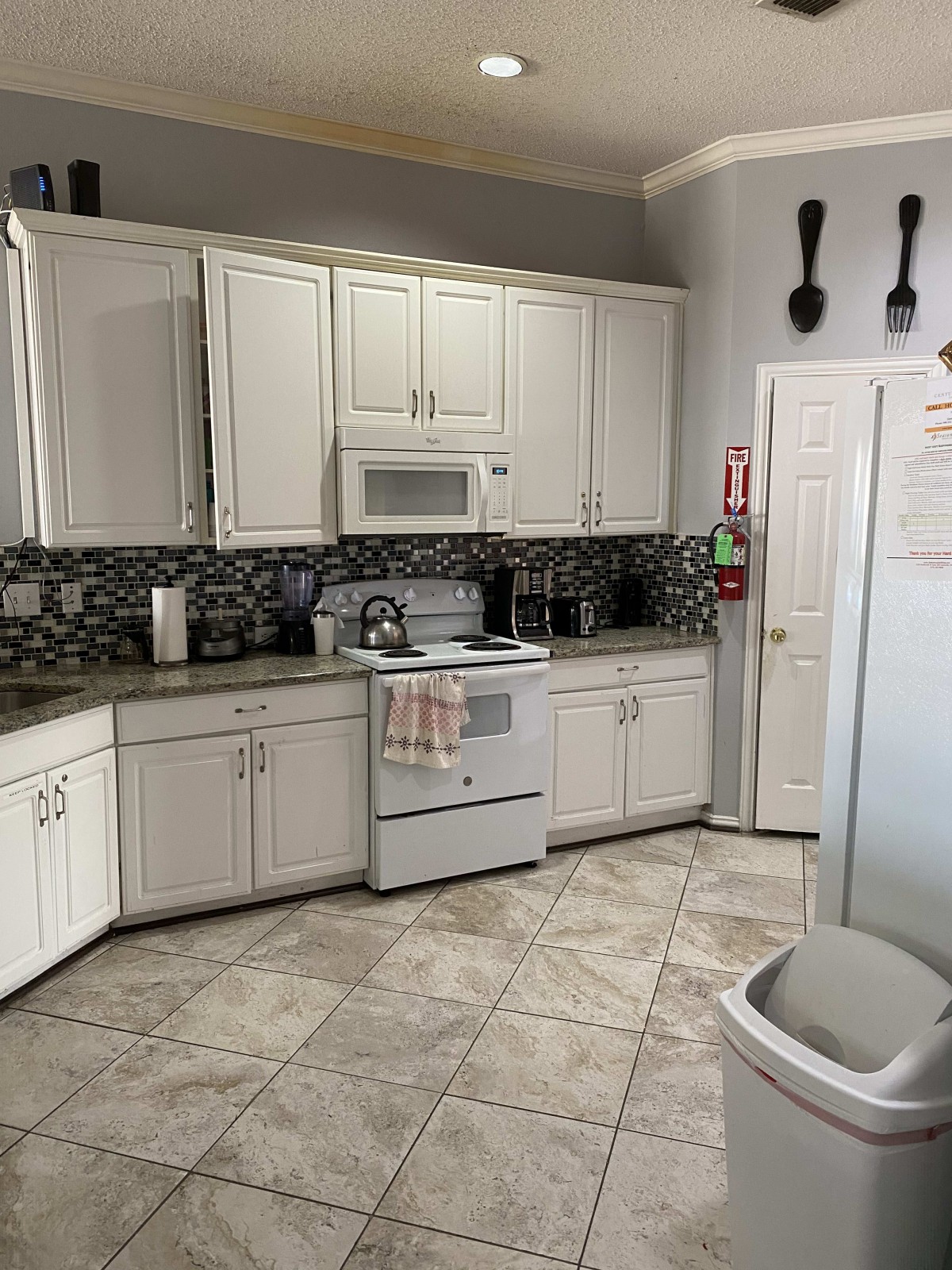 A modern kitchen with white cabinetry and tiled flooring.