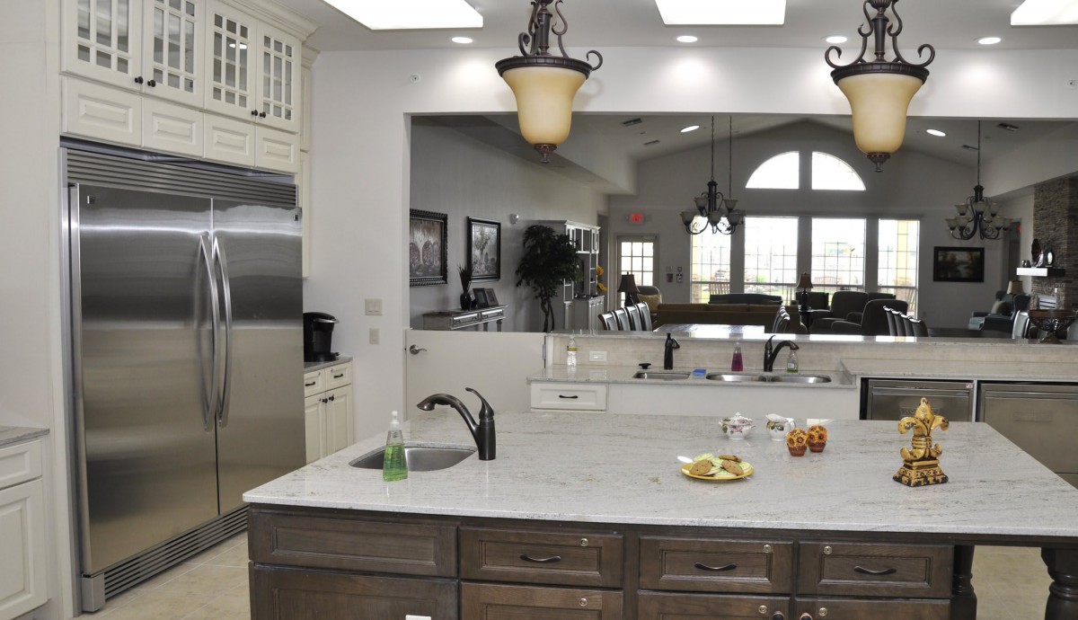 A modern kitchen with a large island and elegant lighting.