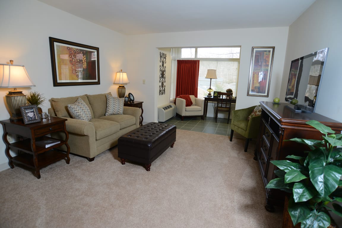 A cozy living room with a sofa, armchair, and coffee table, featuring elegant decor and soft lighting.