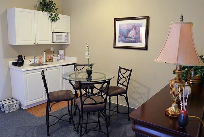 Cozy kitchen and dining area with a glass table and chairs, featuring cabinets, a microwave, and wall art.