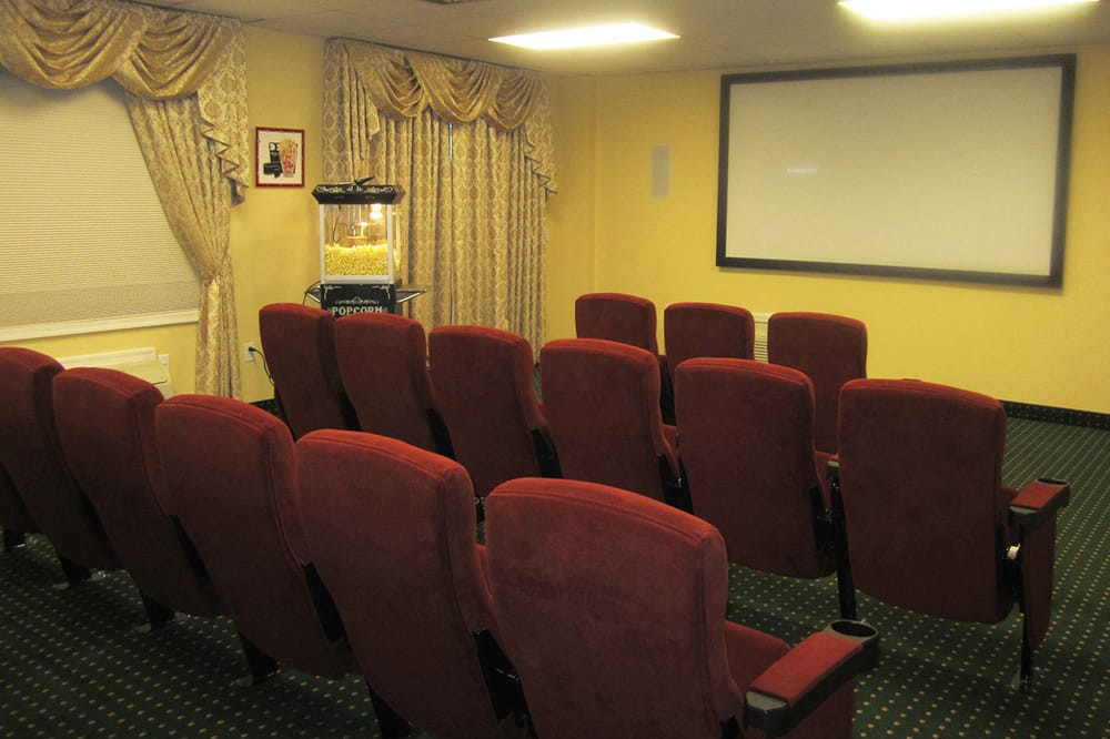 A small home theater room with red seating and a popcorn machine.
