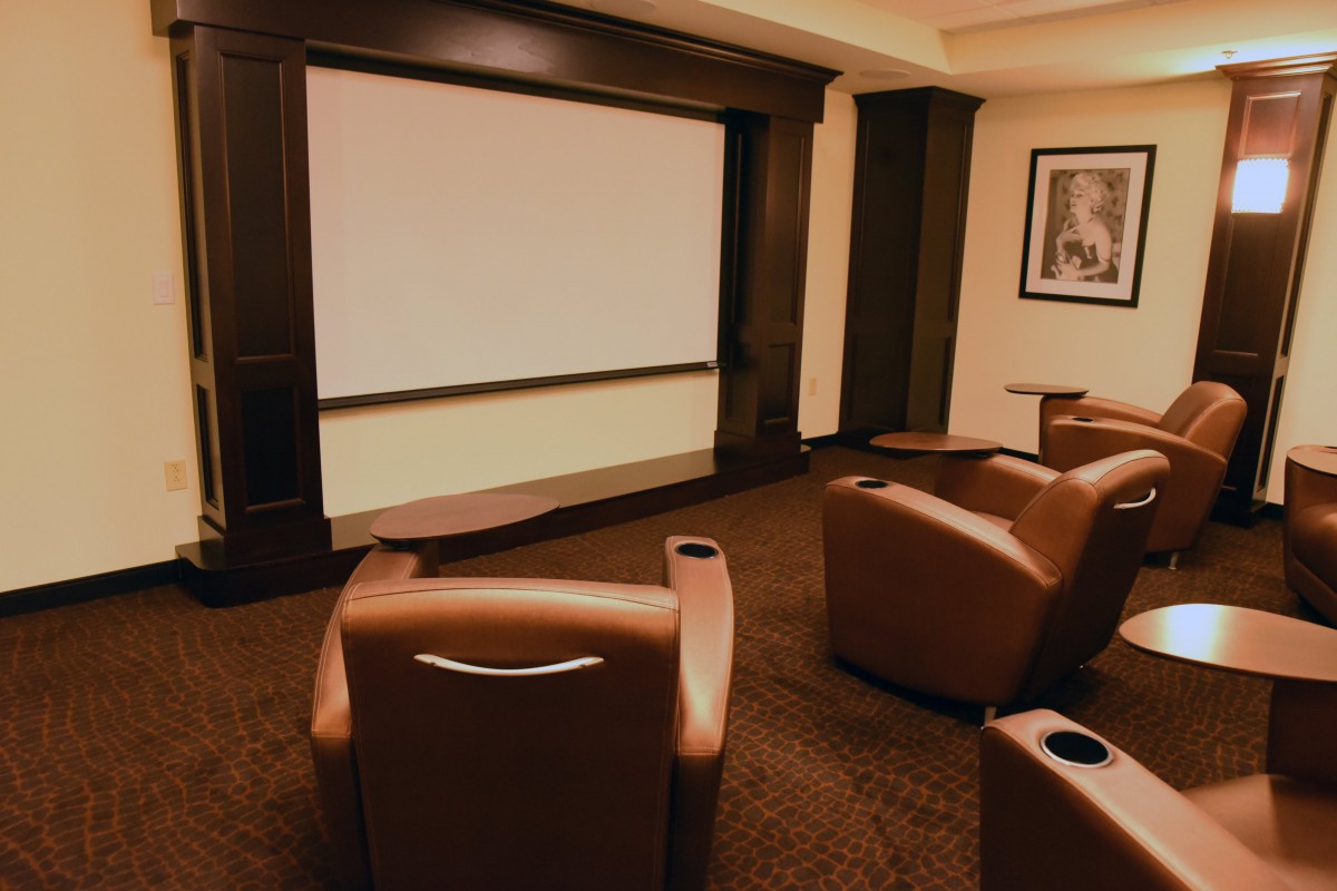 A cozy home theater with comfortable seating facing a large screen.