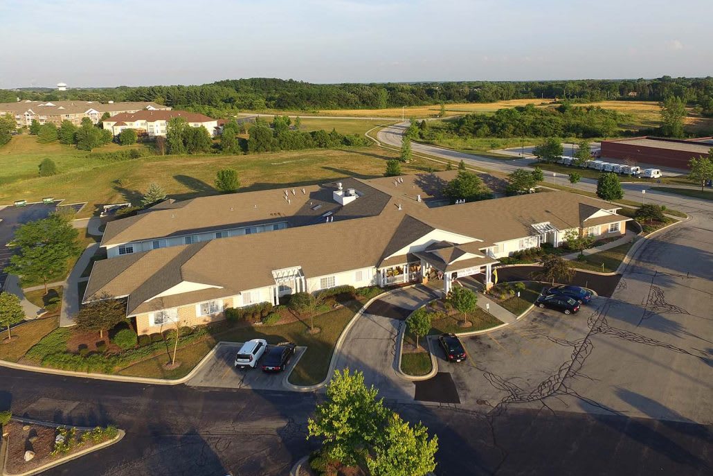 Aerial view of a commercial building with surrounding landscape and parking area.