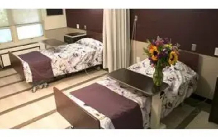 A hospital room with two beds and a vase of flowers.