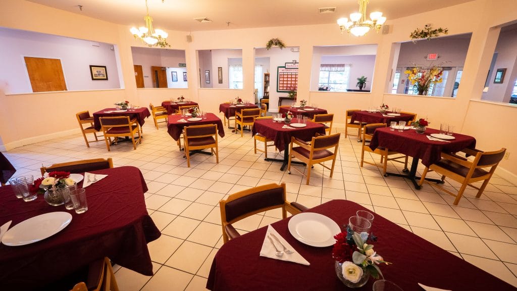 A spacious restaurant dining area with neatly arranged tables and chairs, adorned with elegant chandeliers.