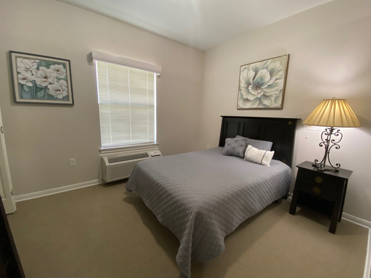 A cozy bedroom with a neatly made bed and soft lighting.