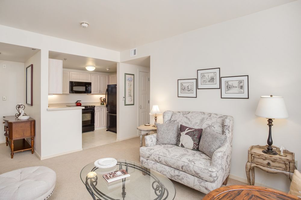 A cozy living room with a view of the kitchen, featuring comfortable seating and stylish decor.