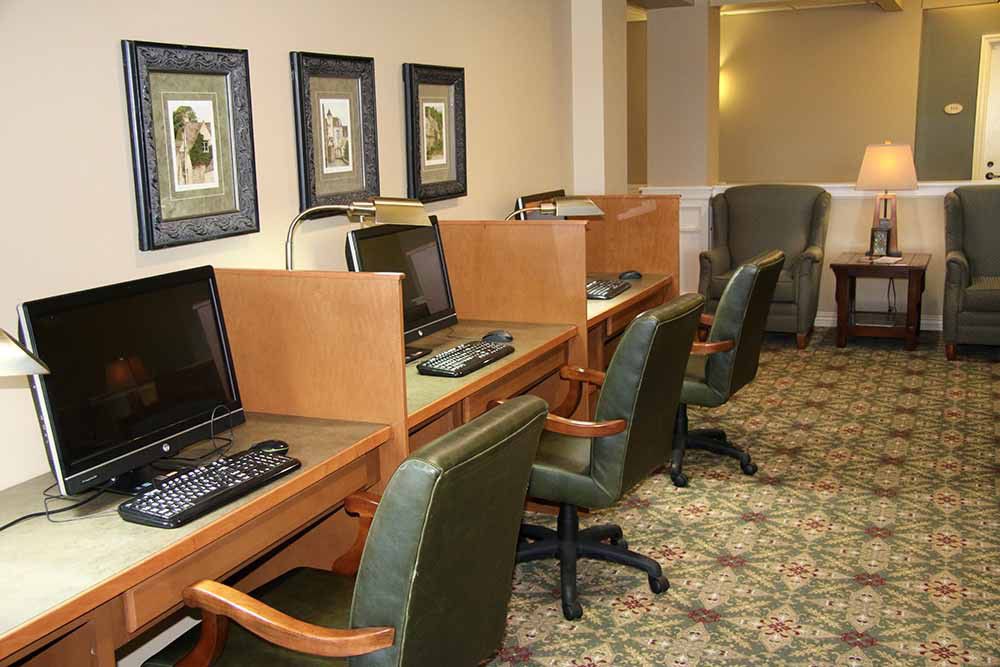 A row of computer workstations with chairs in an office setting.