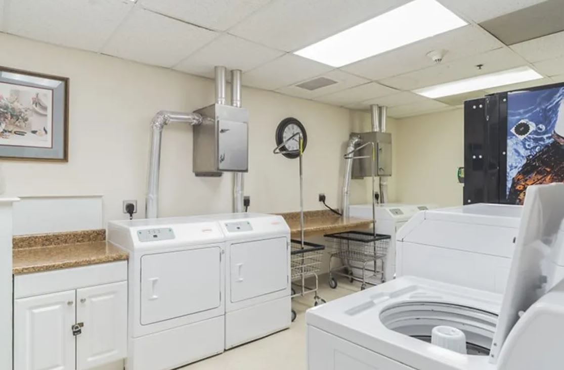 A clean and organized laundry room with washers and dryers.