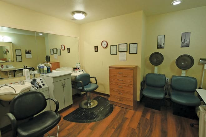 A cozy hair salon interior featuring chairs, a mirror, and a hair dryer.