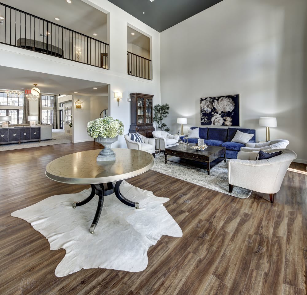 A spacious and modern living room with high ceilings and wood flooring, featuring elegant furniture and abundant natural light.