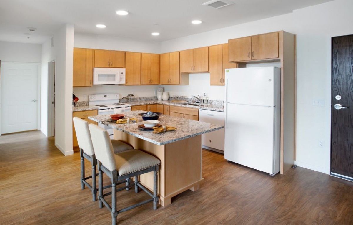 A modern kitchen with wooden cabinets, an island, and various appliances.