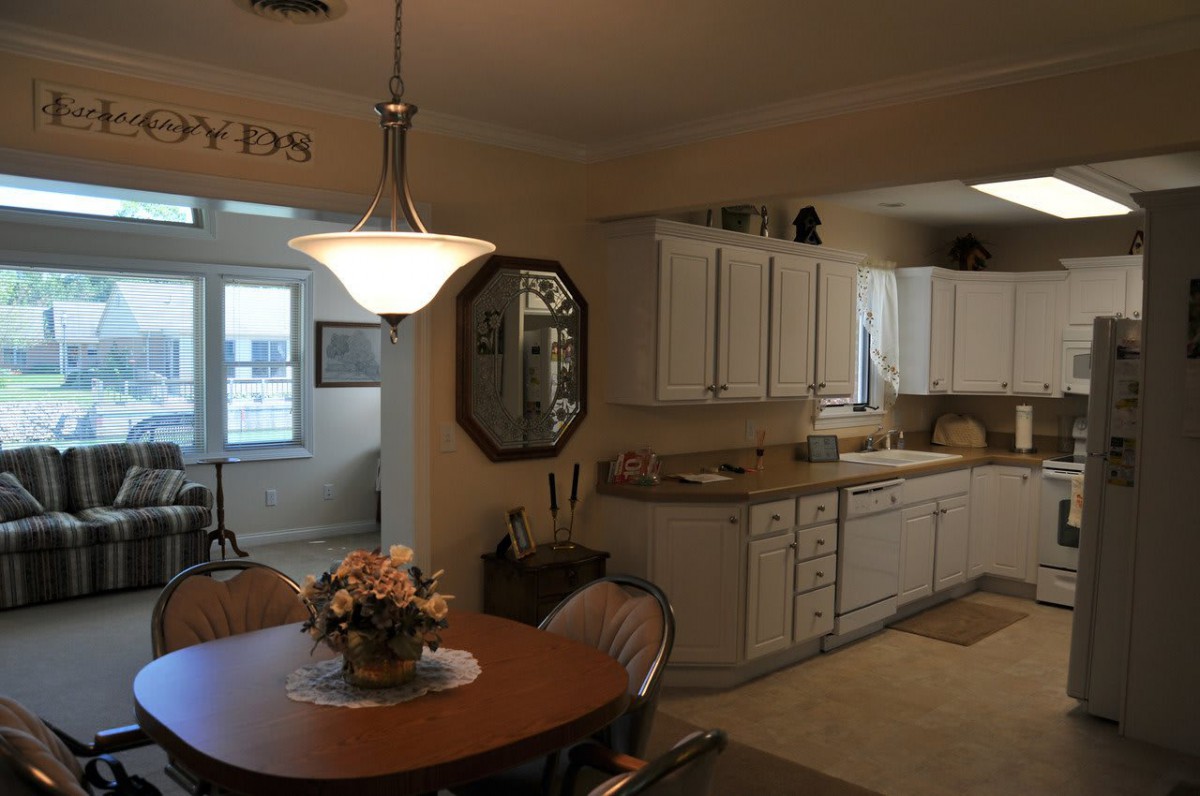 A cozy kitchen with a dining area, featuring white cabinets and a central light fixture.