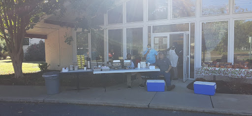 An outdoor setup featuring a food and beverage service table, with people preparing to serve.