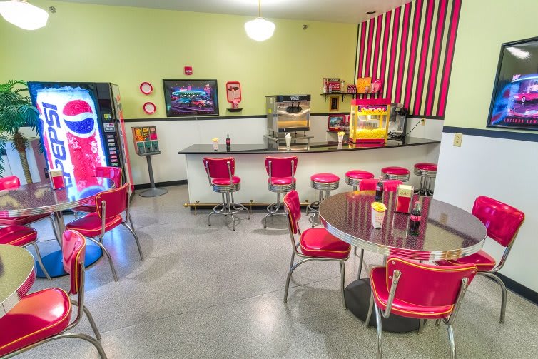 A retro-style diner with vintage decor, featuring red seating and a popcorn machine.