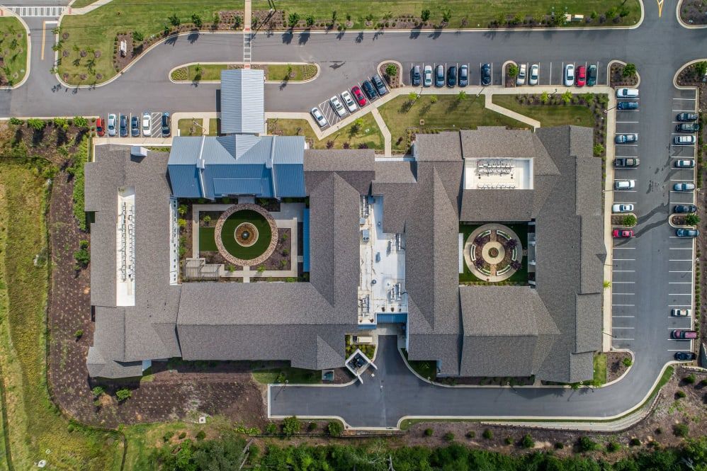 Aerial view of a building complex with parking lots and landscaped gardens.