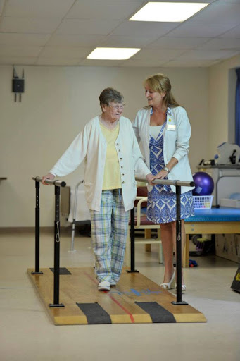 A physical therapist assists an elderly patient in walking during a rehabilitation session.