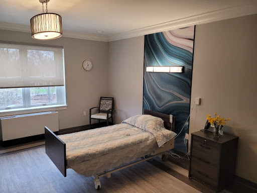 A modern hospital room featuring a bed, bedside table, and soothing wall design.