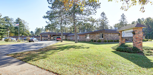 A peaceful residential building surrounded by green grass and trees.