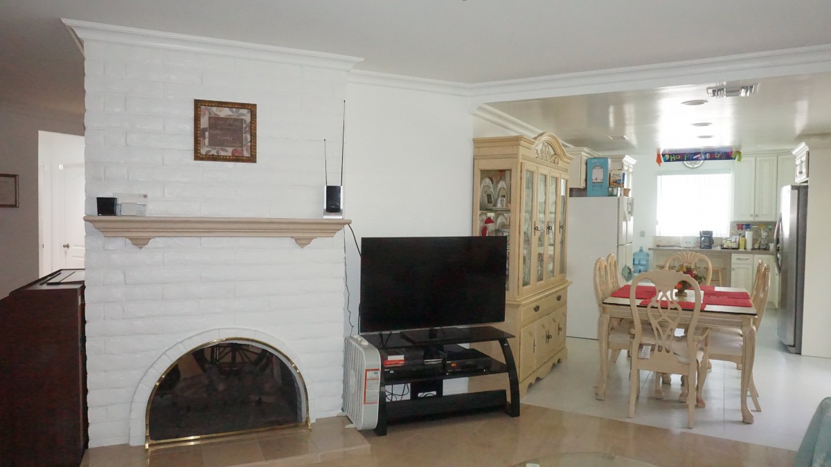A cozy living room with a fireplace, TV, and dining area in the background.
