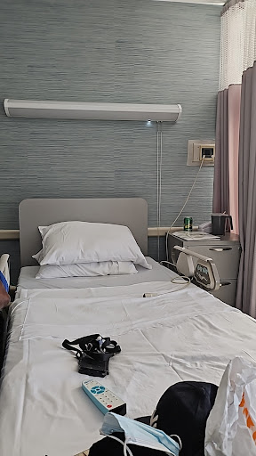 A view of a hospital patient room, featuring a neatly made bed and basic medical equipment.