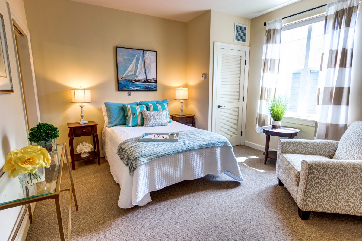 A cozy and well-decorated bedroom with a bed, artwork, and natural light from a window.