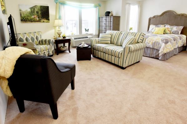 A cozy living room with a striped sofa, armchairs, and light carpeting.