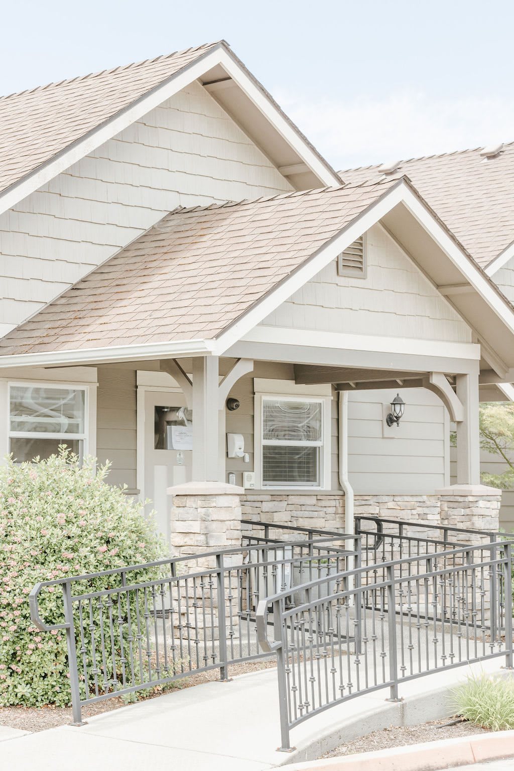 A light-colored house with a ramp leading to the front porch.