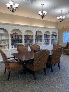 A cozy library room with bookshelves, a table, and chairs.
