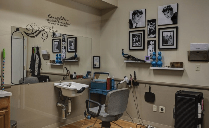 A cozy barber shop interior with a styling chair, mirror, and wall decorations.