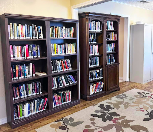 A warm and inviting space featuring two wooden bookshelves filled with various books, complemented by a decorative area rug.