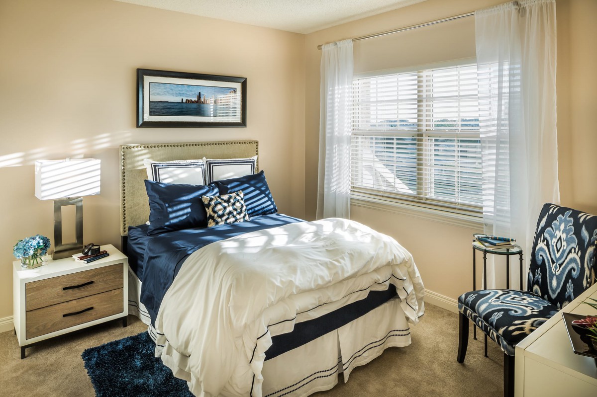 A cozy bedroom with a neatly made bed and natural light streaming through the window.