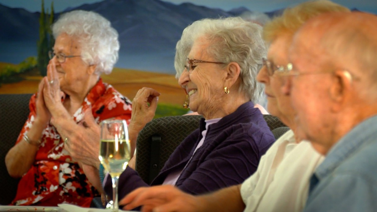 A group of elderly people enjoying a gathering with wine.