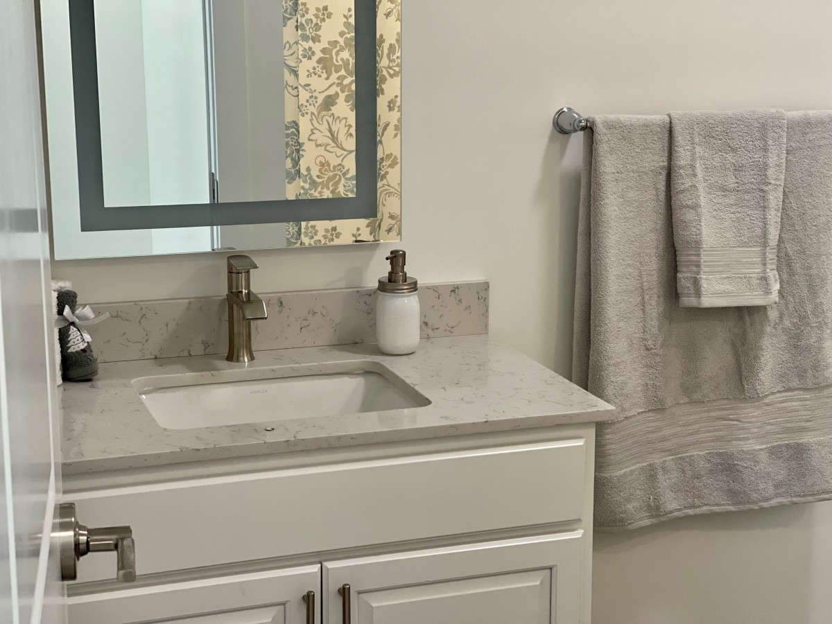 A modern bathroom with a marble countertop, mirror, and neatly hung towels.